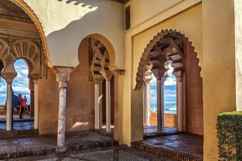 An interior courtyard with arches, columns, and a view of the sea. 2