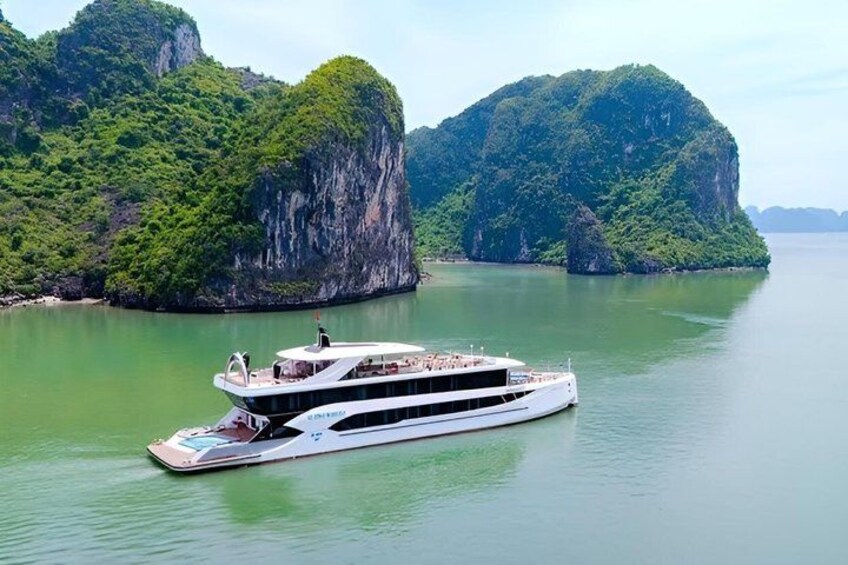 A white boat with a balcony on a calm river surrounded by lush green cliffs. 4