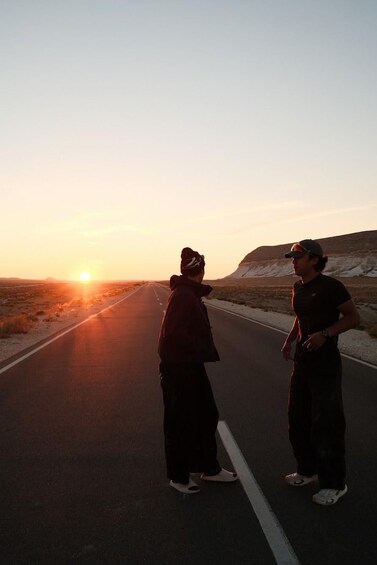 Two people standing on a road during sunset. 5