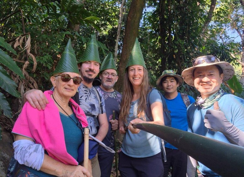 A group of people in a forested area, some wearing hats and holding tools. 2