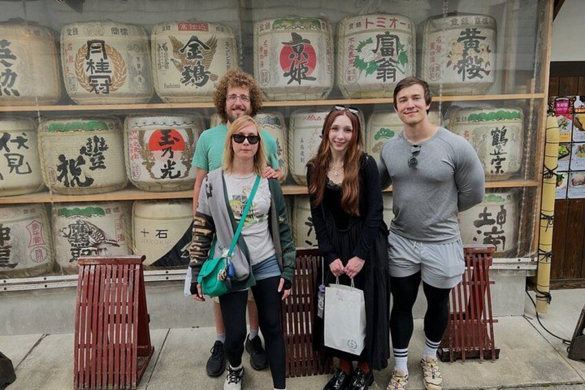 Four people standing in front of a display with large containers and Japanese characters. 5