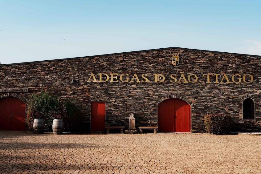 A building with a stone facade and the sign 'ADEGAS D SÃO TIAGO'. 1