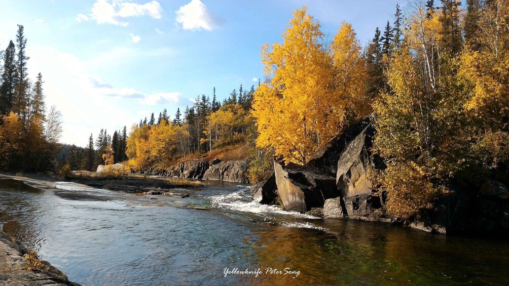A river flowing through a forest with autumn-colored trees and rocky outcrops. 2