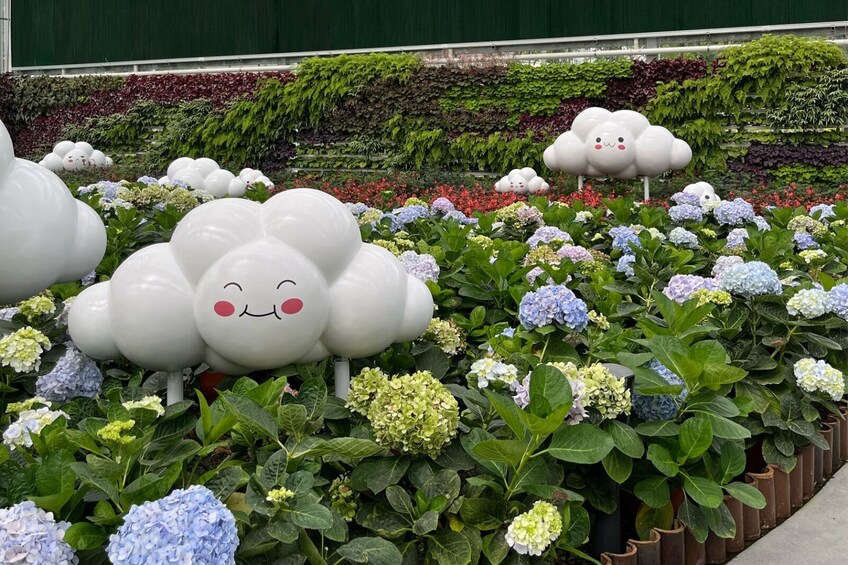 A garden with large white cloud-shaped sculptures and hydrangea flowers. 4