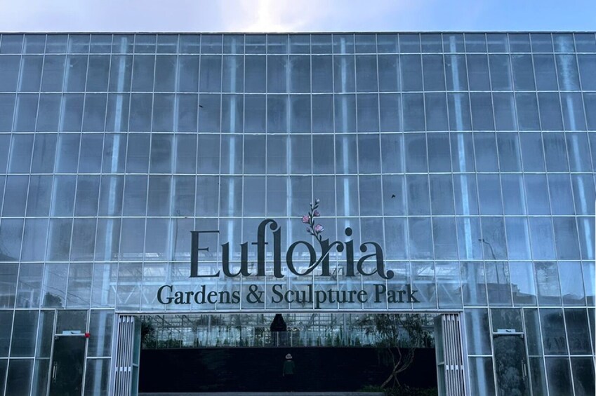 A modern glass building with the name 'Euforia Gardens & Sculpture Park' displayed prominently. 2