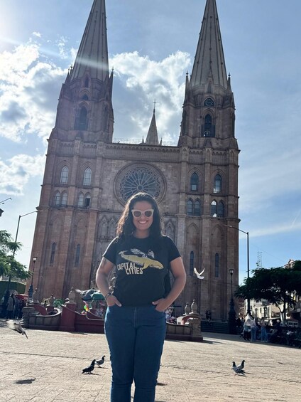 A person standing in front of a large cathedral with two tall spires and a large rose window. 4