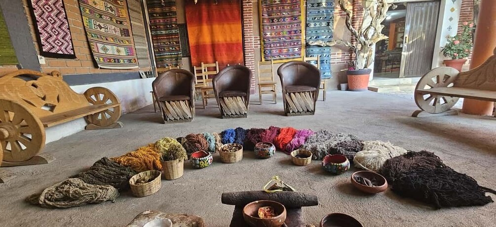 A room with chairs, colorful textiles, and a wooden cart. 1