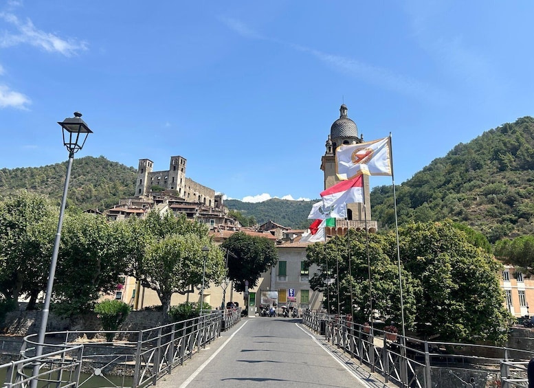 A bridge leading to a historic town with a prominent tower and flags. 5