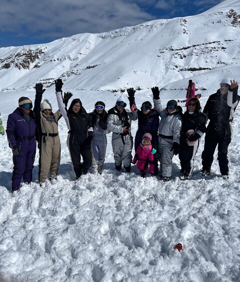 A group of people on a snowy mountain with snow-covered terrain and rocky outcrops in the background. 2
