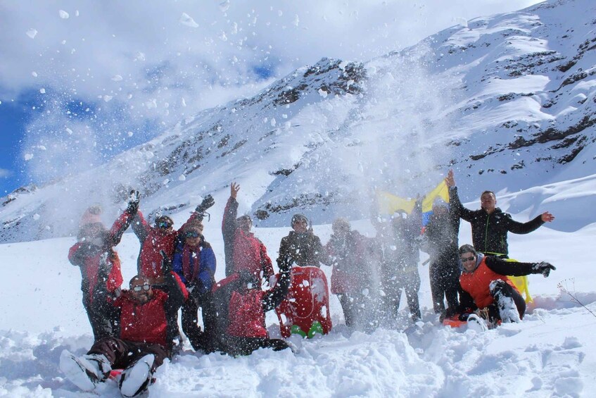 A group of people in a snowy mountainous area, some with snowboards and others with skis, enjoying winter sports. 1