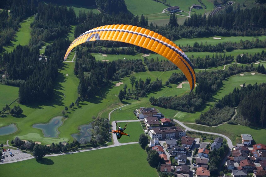 A paraglider flying over a golf course with houses in the foreground. 4