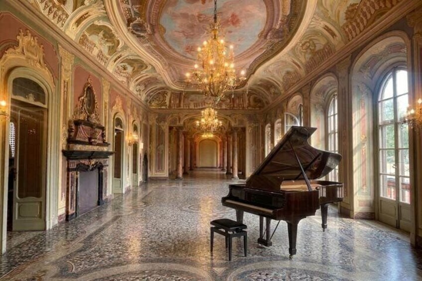 A grand hall with a grand piano, ornate ceiling, and large windows. 3