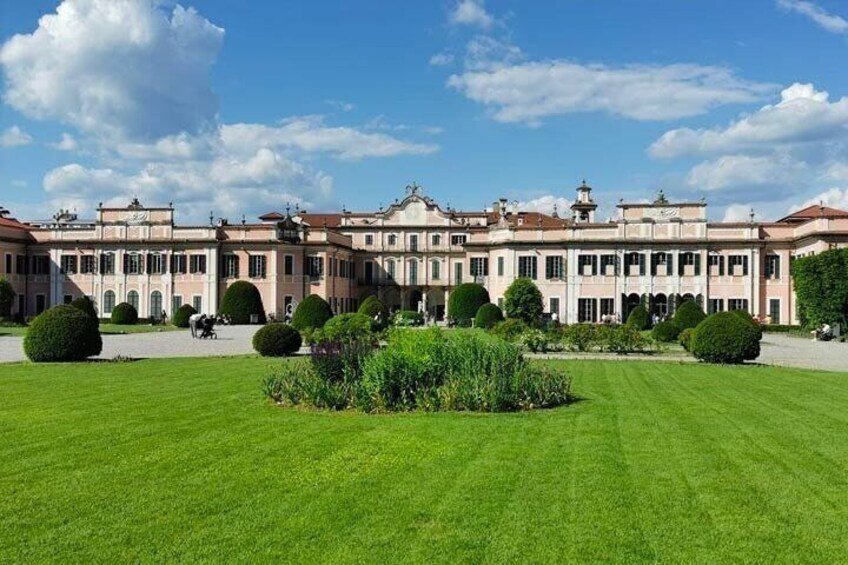 A grand classical building with symmetrical architecture, manicured lawns, and formal gardens. 2