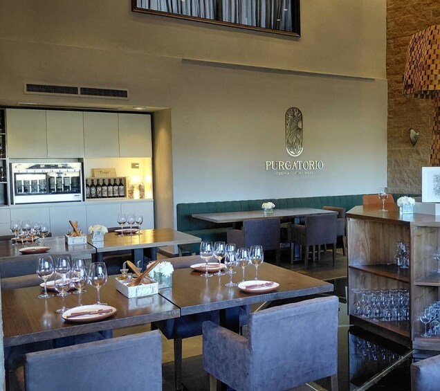 A restaurant interior with tables set for dining, a bar area, and a wall-mounted wine display. 3