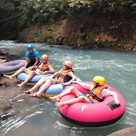 People on inflatable rafts in a river surrounded by greenery. 4