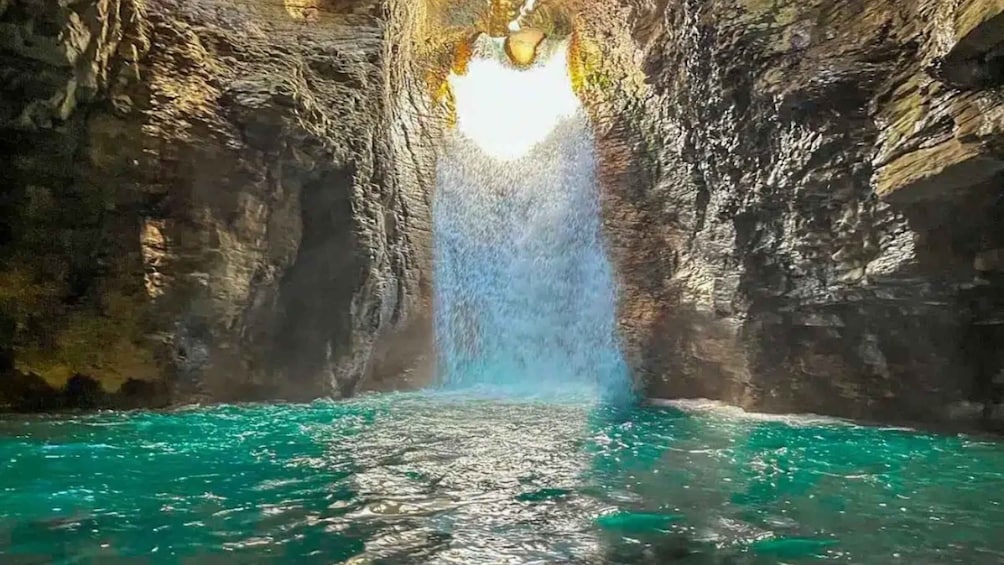 A cave with a water stream flowing into a turquoise pool. 5