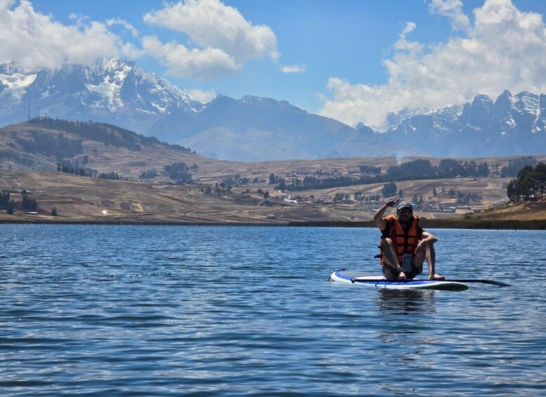 A person sitting on a paddleboard in a lake with mountains in the background. 4