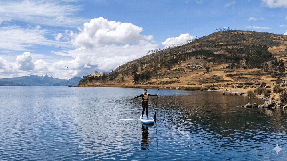 A person paddleboarding on a calm lake with mountains in the background. 4
