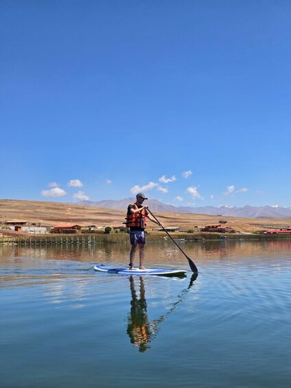 A person paddleboarding on a calm lake with mountains in the background. 3