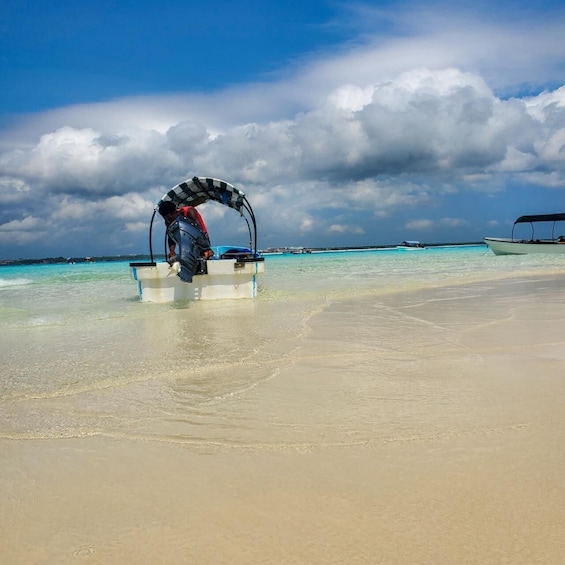 A beach with clear turquoise water, a person in a kayak, and a boat in the background. 4