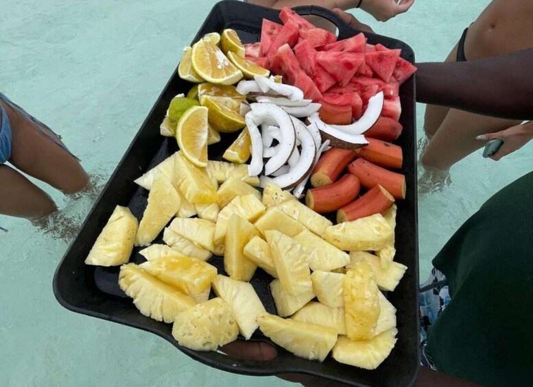 A tray of food including pineapple, watermelon, onions, and hot dogs. 2