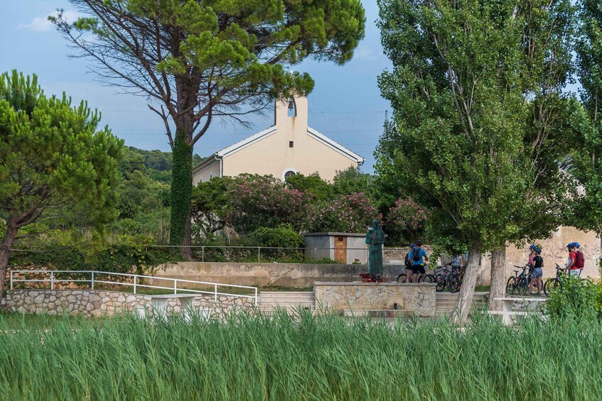 A stone bridge, a church, and cyclists in a park. 2