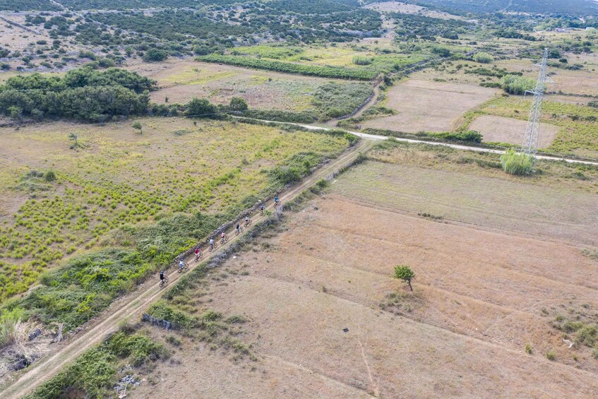 A rural landscape with fields, a dirt road, and a power line tower. 3