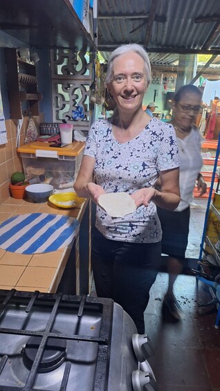 A person holding a flatbread near a gas stove in a kitchen. 2