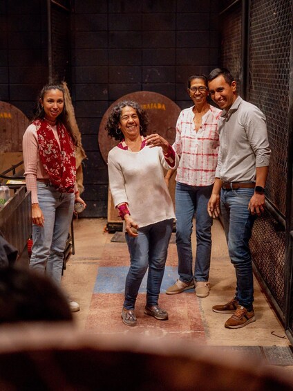 A group of people standing in a dimly lit room with wooden barrels in the background. 5