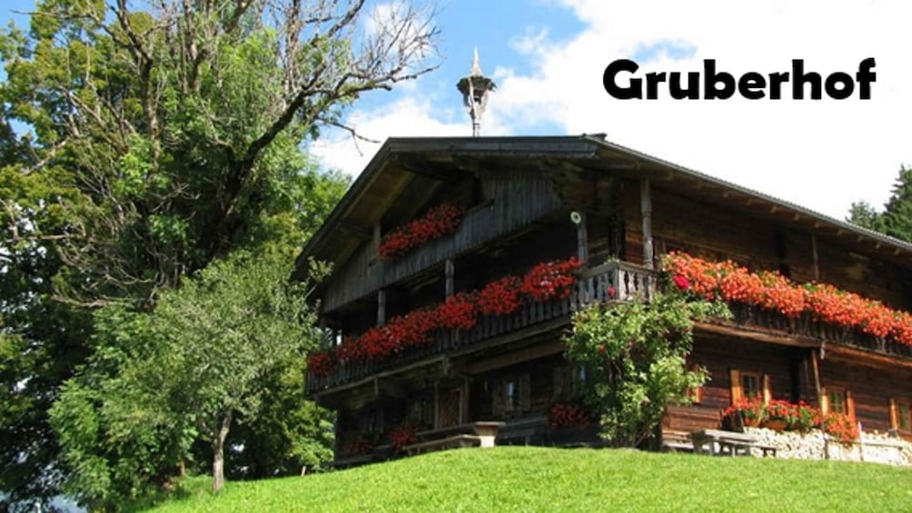 A traditional wooden building with balconies adorned with red flowers, surrounded by lush greenery. 3