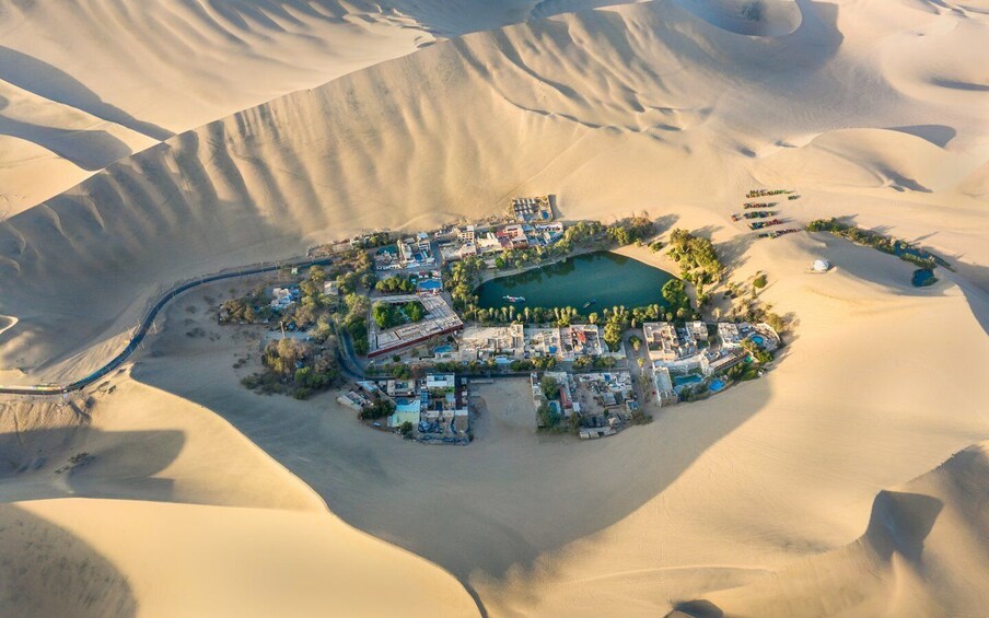 A desert resort with a swimming pool, surrounded by sand dunes. 2