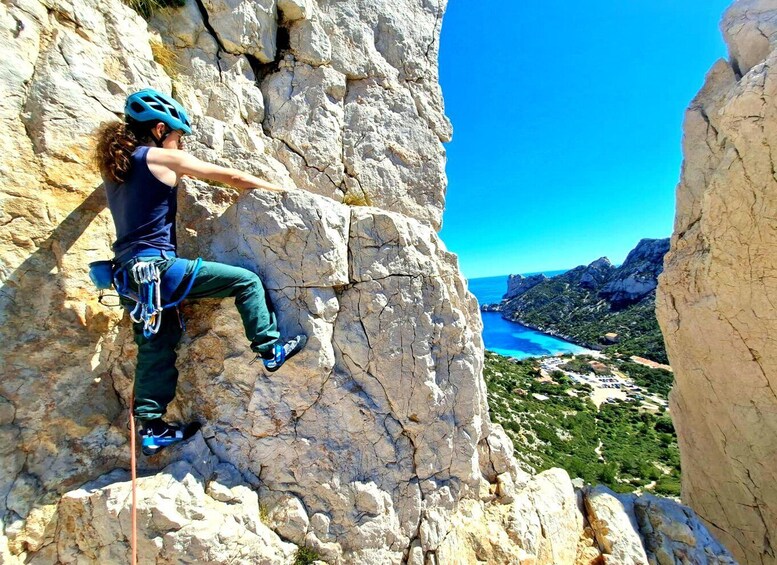 A person rock climbing on a cliff with a scenic view of a coastal landscape and a clear blue sky. 2