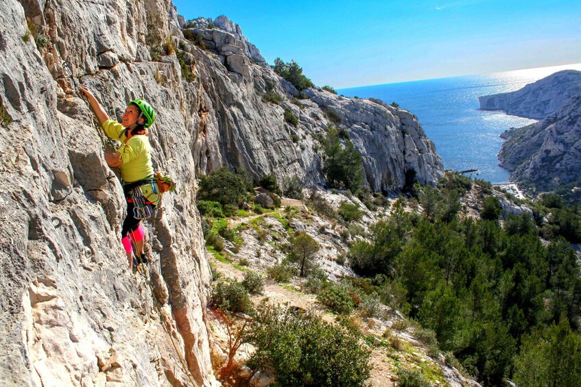 A person rock climbing on a rocky cliff with a coastal view. 3