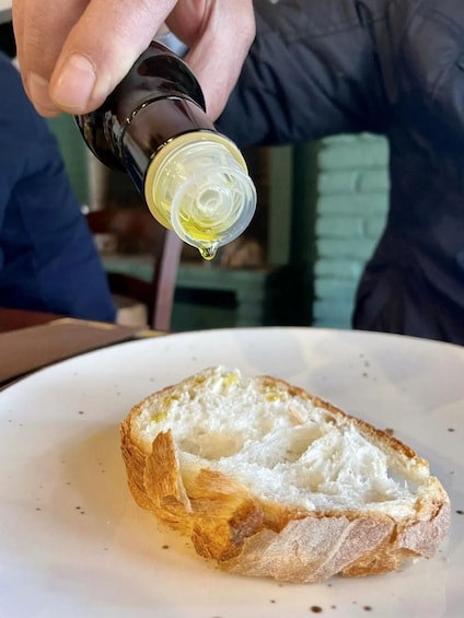 A hand pouring olive oil onto a slice of bread. 5