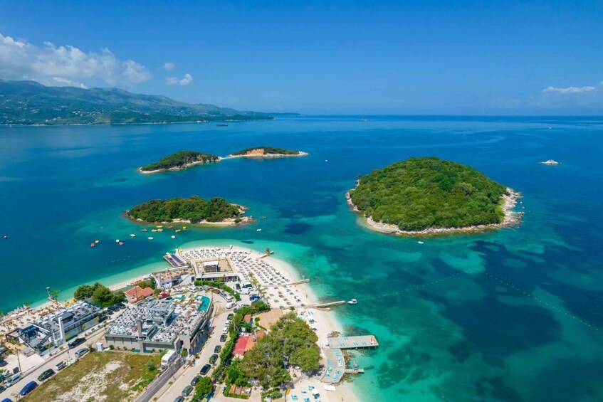 An aerial view of a coastal area with a beach, parking lot, and several small islands. 1