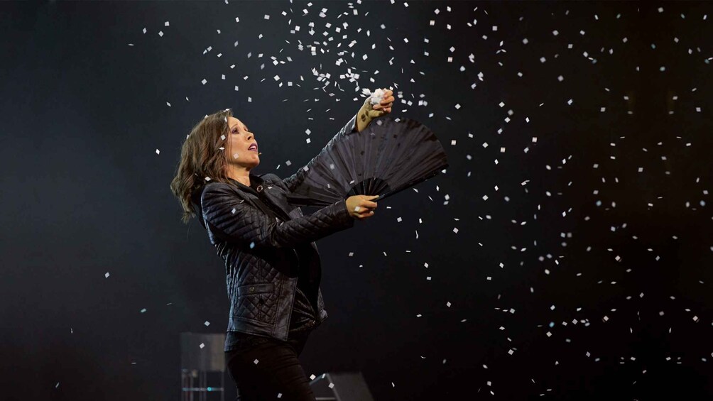 A person holding a fan with confetti flying around. 1