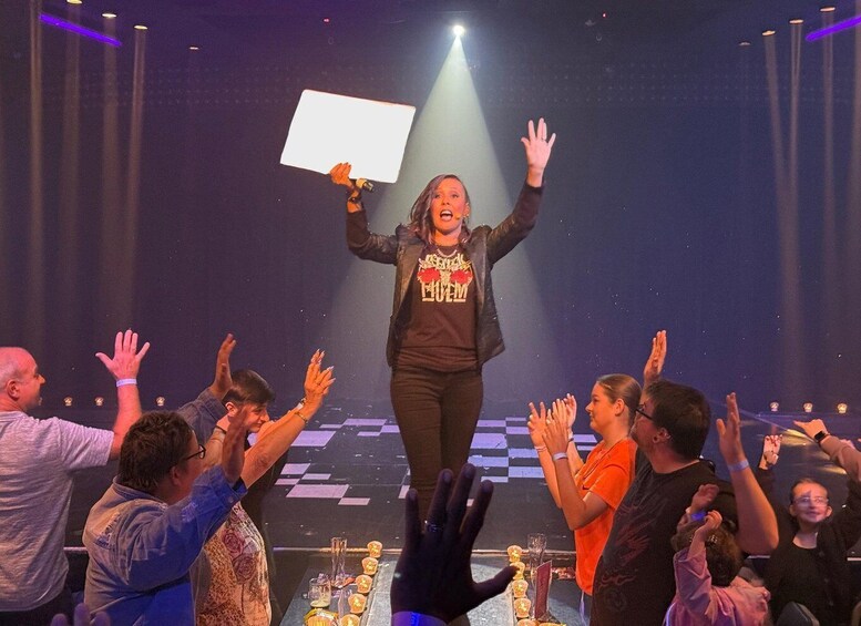 A person holding a sign on a stage with a crowd raising their hands. 4