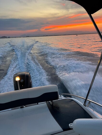 A boat moving through water with a sunset in the background. 3