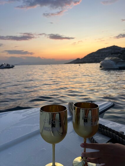 Two golden goblets on a boat with a sunset and calm sea in the background. 1