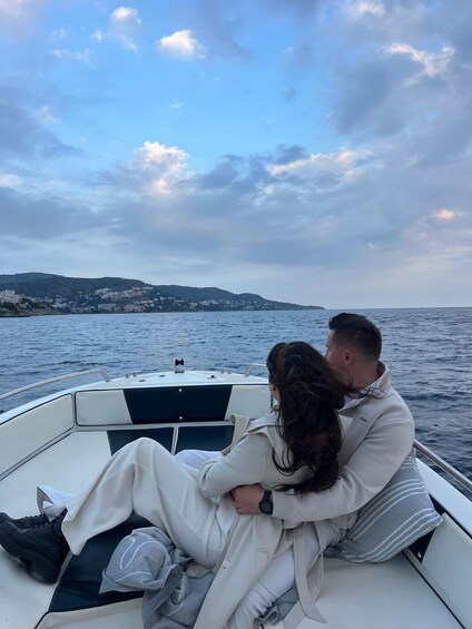 A couple embracing on a boat with a coastal landscape in the background. 4