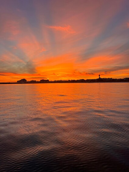 A sunset over a calm body of water with a city skyline in the background. 5