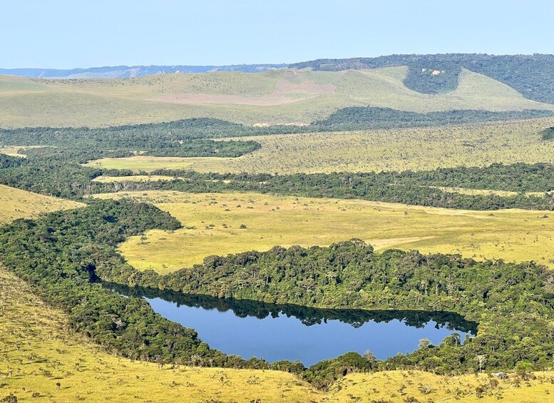 A landscape with a lake surrounded by hills and sparse vegetation. 3