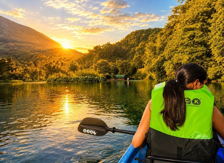 A person kayaking on a calm river with a sunset in the background. 2