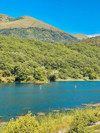 A lake surrounded by lush green hills under a clear blue sky. 3