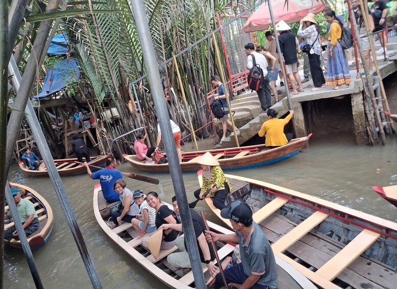 People in wooden boats on a river, surrounded by bamboo structures and greenery. 4