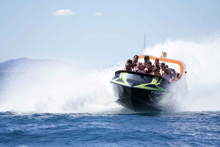 A speedboat with passengers, creating a large wake in the water. 1
