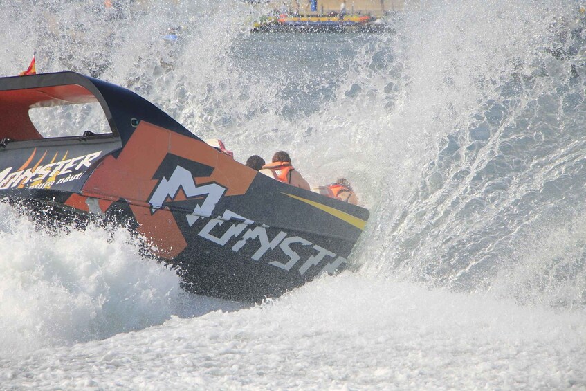 A speedboat with 'Monster' branding navigating a large wave. 3
