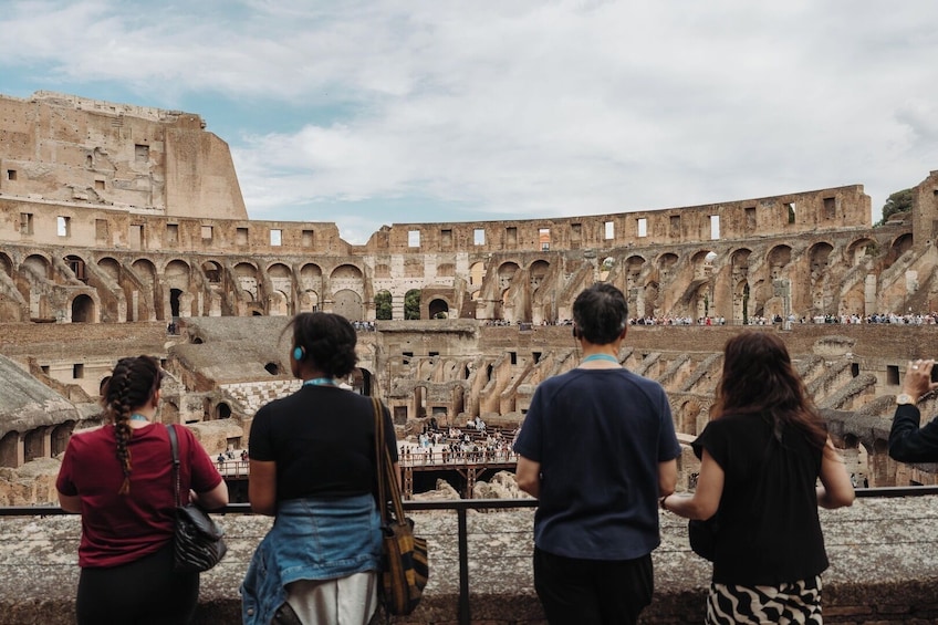 Ein historisches Amphitheater mit mehreren Stufen von Arkaden und einer Besuchermenge. 2