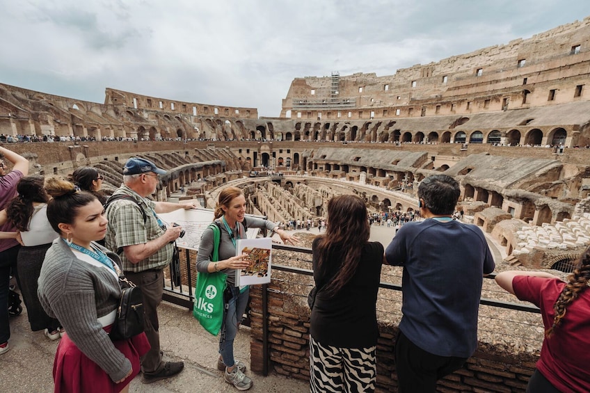 Eine Gruppe von Touristen vor einem antiken Amphitheater mit einer zentralen Bühne und mehreren Sitzreihen. 1