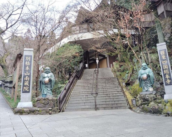 A temple entrance with stone statues, a staircase, and traditional architecture. 1